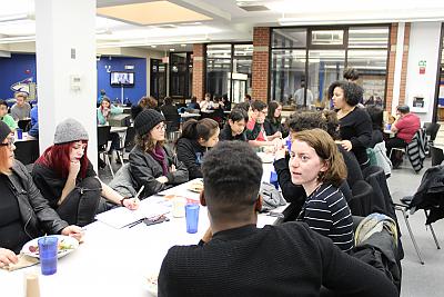 Another long table shot of students who participate in Center for Diversity and Inclusion programming gathering for dinner in the Dining Hall. This time, they are engaged in conversation rather than posing for a picture. 
